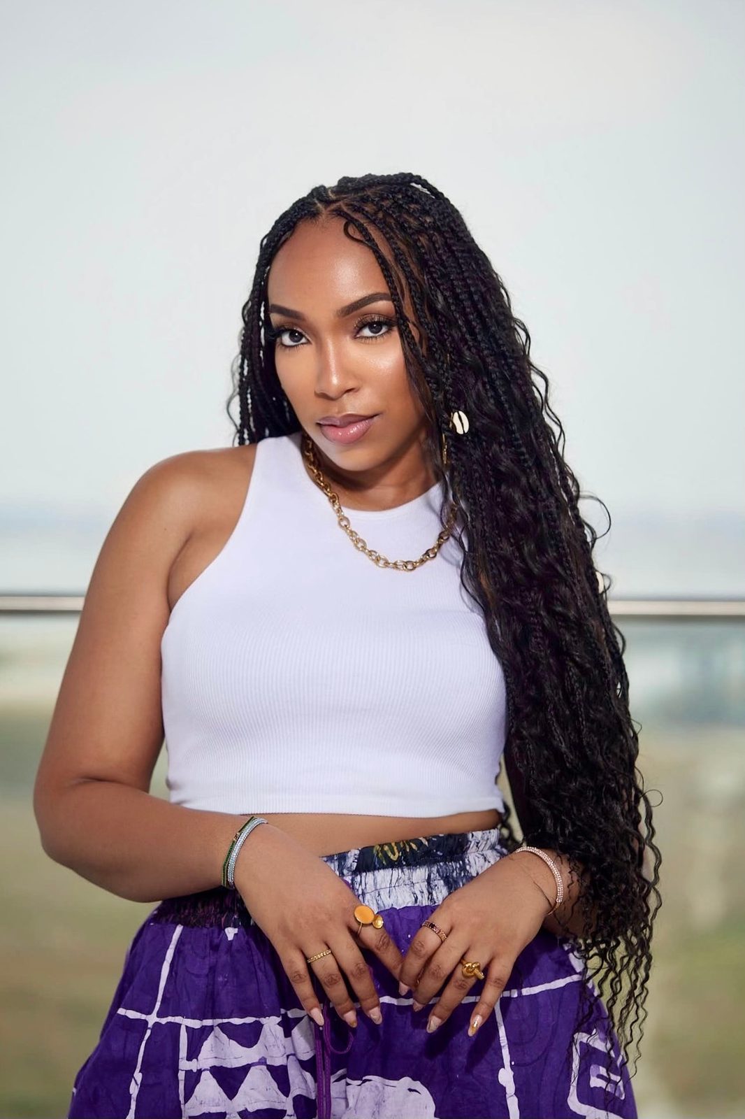 Portrait of Eki Ogunbor in a white top with long braids and a gold chain